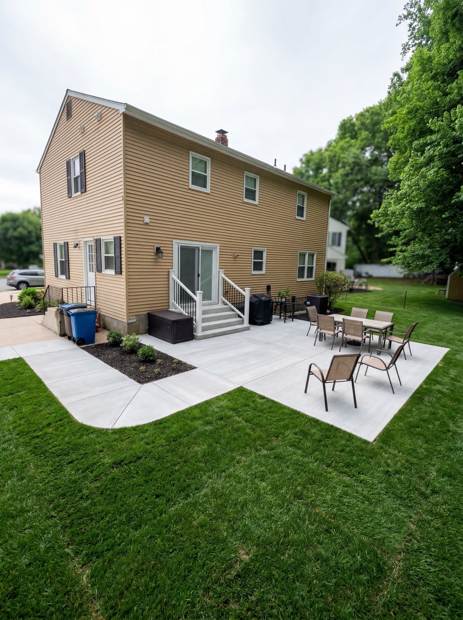 Backyard concrete patio with seating by Green Life Landscaping